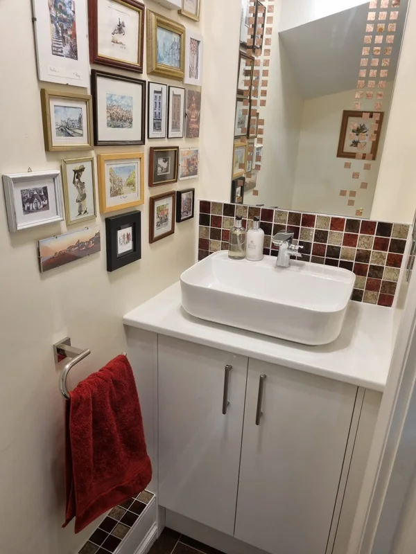 Downstairs cloakroom with a countertop basin on a white vanity unit and a mosaic tiled splashback