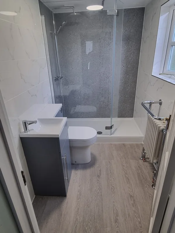 Shower room with a glass enclosure, grey stone-effect wall, fitted vanity unit and a traditional column radiator